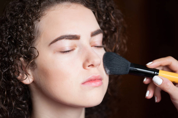 Beauty and makeup concept - closeup portrait of beautiful woman getting professional make-up with brush. - Photo, Image