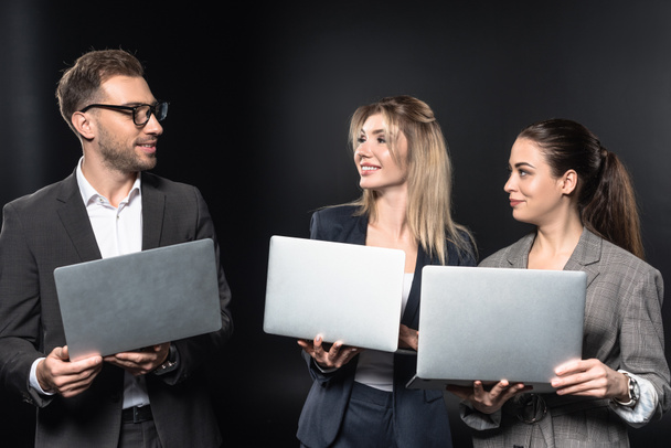 group of happy business people working with laptops together isolated on black - Photo, Image