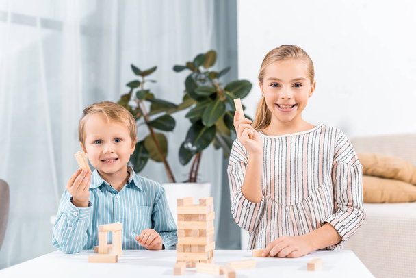 selective focus of happy adorable children playing blocks wood tower game at home - Photo, Image