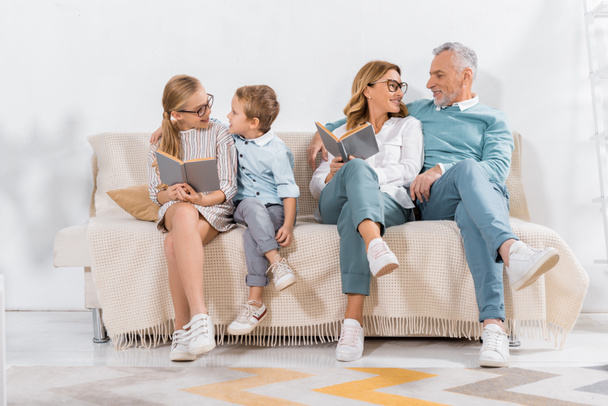 boldog unokák és a nagyszülők, a kanapén, otthon, olvasás - Fotó, kép