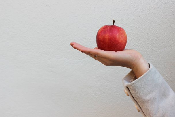 femme dans un manteau tient une pomme rouge savoureuse
 - Photo, image