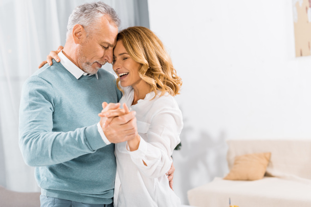 side view of happy mature couple dancing face to face at home - Photo, Image