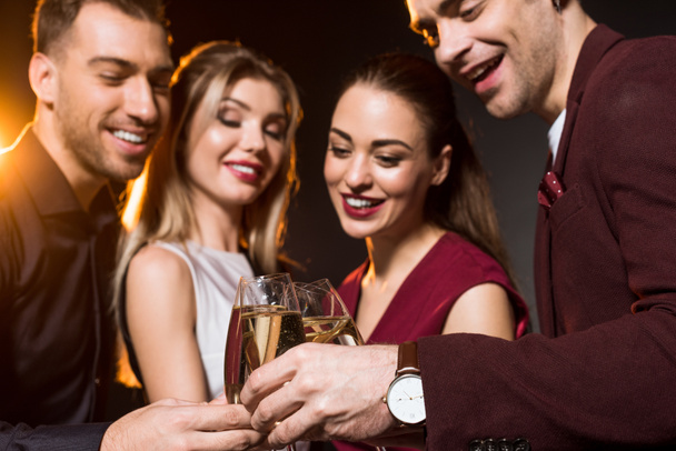 grupo de amigos tintineo copas de champán durante la fiesta en negro
 - Foto, Imagen