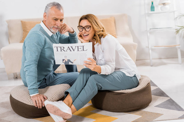 χαμογελώντας ζευγάρι διαβάζοντας εφημερίδα ταξίδια στο σπίτι - Φωτογραφία, εικόνα