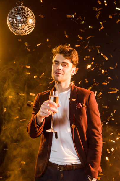 handsome young man with champagne celebrating christmas with falling confetti - Fotoğraf, Görsel