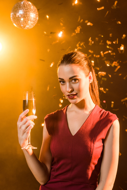 attrayant jeune femme avec verre de champagne sous confettis tombant, concept de Noël
 - Photo, image