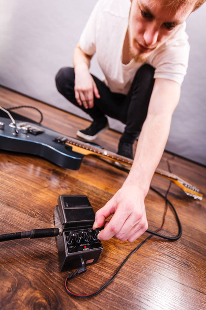 Hombre con instrumento musical instalando efectos de caja de audio de guitarra y cables en estudio de música - Foto, Imagen
