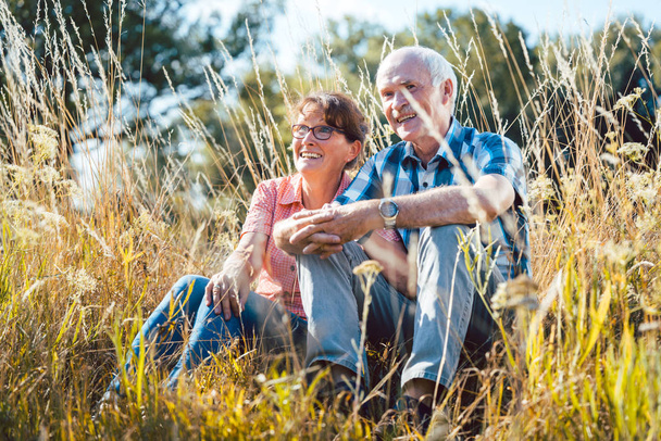 Vanhempi pari istuu nurmikolla nauttien
 - Valokuva, kuva