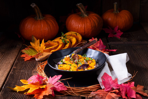zapečená Vegetariánská dýňová s pohankovými kroupami a švestky a tymiánem v desce s podzimní listy na pozadí  - Fotografie, Obrázek