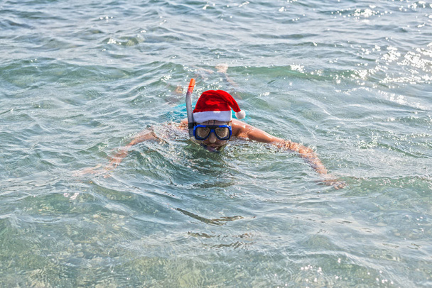 Homem de chapéu de Papai Noel e máscara de mergulho, fundo de Natal com espaço de cópia. Feriados de Ano Novo em países tropicais
. - Foto, Imagem