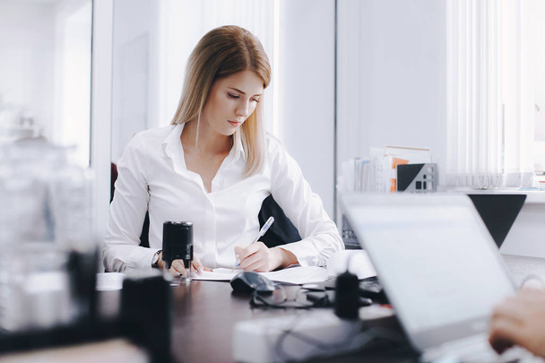 Young attractive blonde is working with documents at table in office. Business portrait - Fotó, kép
