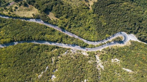 Aerial view of the movement of vehicles on a serpentine mountain road. Croatia. - 写真・画像