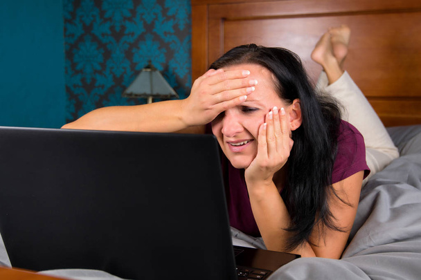 Woman lying on bed and looking at computer. - Photo, image