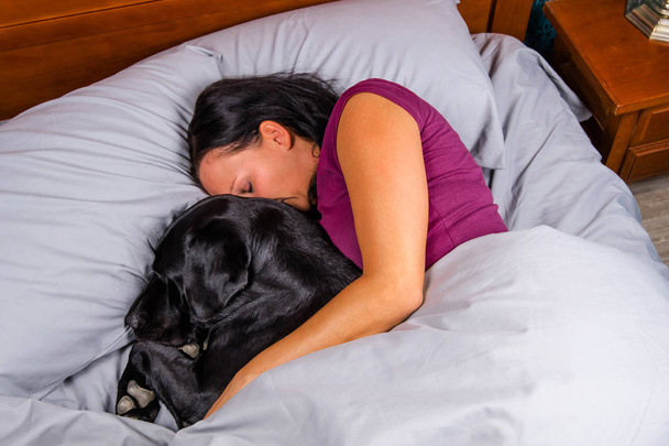 Kadın ile köpek yatakta uyuyor. - Fotoğraf, Görsel