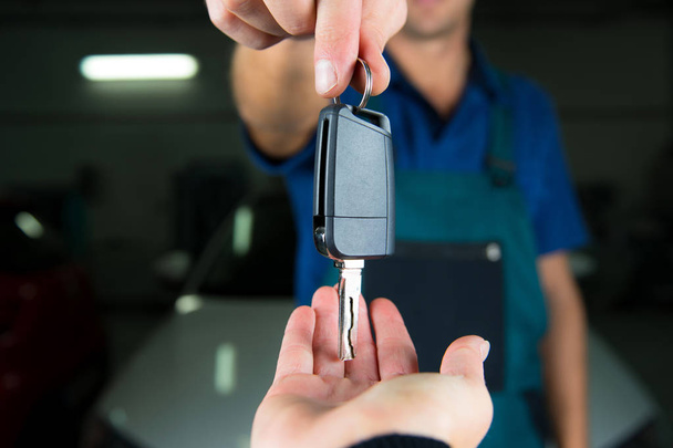 Young car service technician give key of car to customer. - Photo, Image