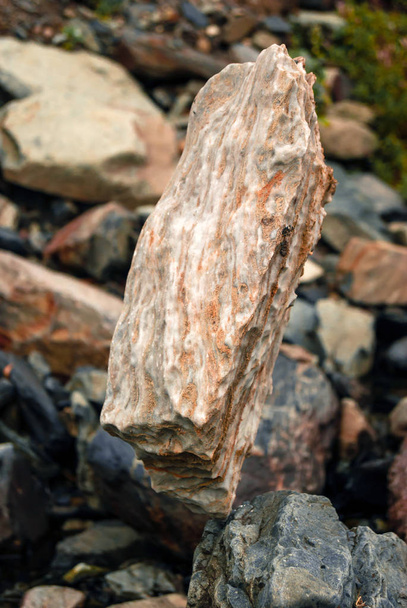 kevyt luonnollinen mukulakivi seisoo pystysuunnassa herkässä tasapainossa toisella kivellä
 - Valokuva, kuva