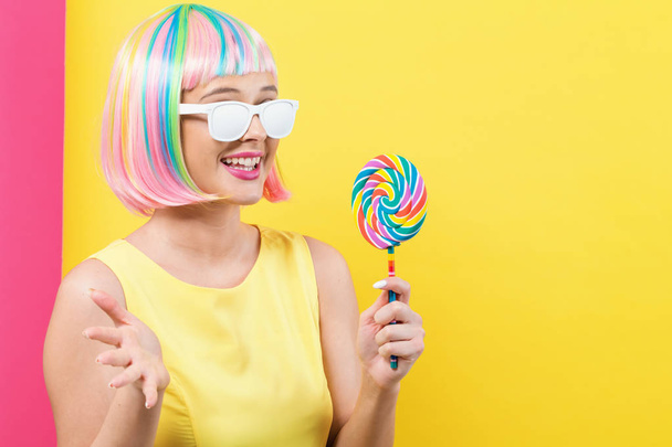 Woman in a colorful wig with a lollipop - Fotoğraf, Görsel