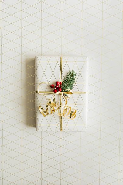 Composición festiva de Navidad / Año Nuevo con caja de regalo, ramas de abeto, bayas rojas y decoraciones doradas. Piso tendido, vista superior
. - Foto, Imagen