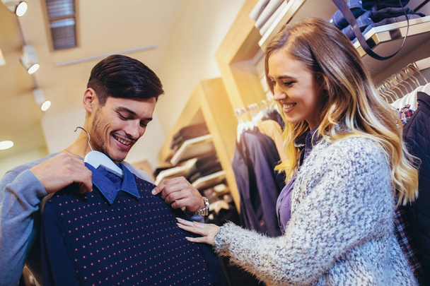 Giovane uomo consulta con la fidanzata durante la selezione di un maglione
 - Foto, immagini