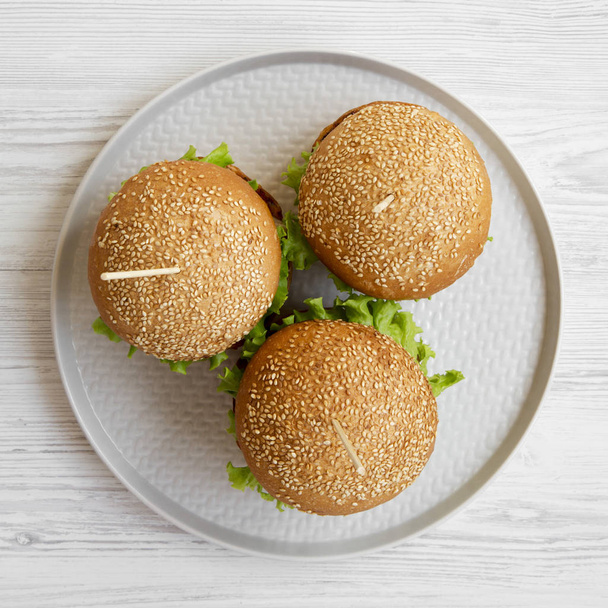Top view, cheeseburgers on grey plate on white wooden background. Flat lay, overhead, from above. Closeup. - Photo, Image