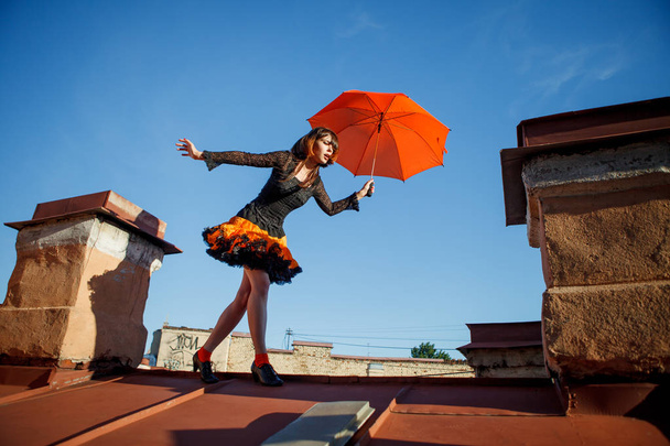 Çatıda bir şemsiye ile genç güzel kadın. Romantik yürüyüş modeli kızlar gökyüzü arka plan üzerinde - Fotoğraf, Görsel