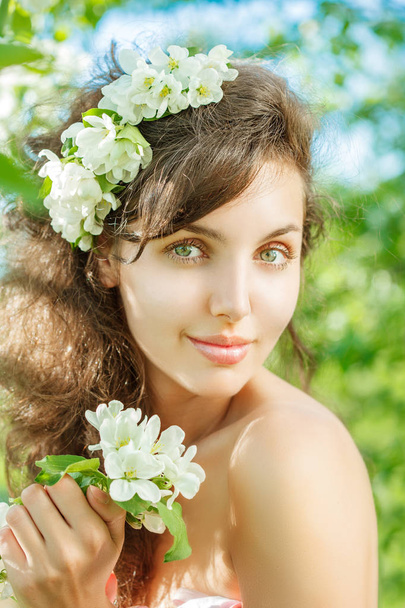 Spring Woman.Beautiful Girl model with spring flowers. Young Female with blooming apple and cherry on the background of a summer garden. Allergy to pollen. - Фото, изображение