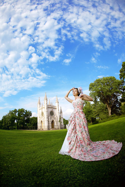 A woman like a princess in an vintage dress before the magic castle - Foto, Imagem