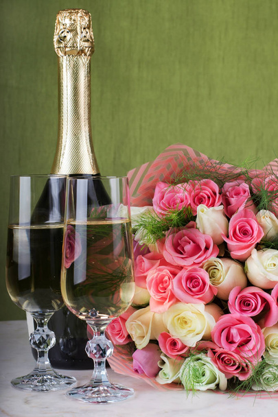 Wedding arrangement. Bridal bouquet, two glasses of champagne and a bottle of champagne on a marble table. Engagement ring with a diamond in a champagne glass. Marriage proposal - Photo, image