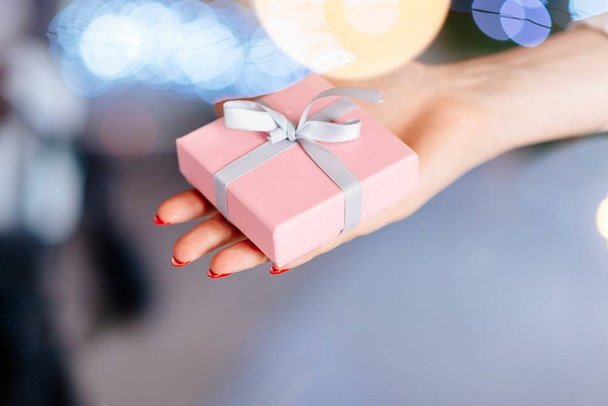Woman holding present in hand. Christmas surprise - Фото, изображение