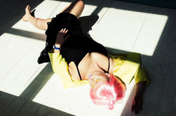  young sensual woman with pink hair in black dress on floor  - Фото, изображение