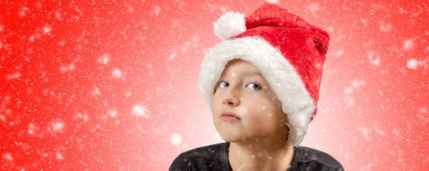 jovem menino entediado com boné de Natal e atmosfera de inverno em fundo brilhante e nevado
 - Foto, Imagem