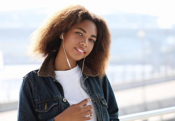 lifestyle concept: Young african american girl using mobile phone and headphones, smiling - Φωτογραφία, εικόνα