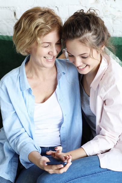 Aged woman and her adult daughter using smartphone at home. - Foto, immagini