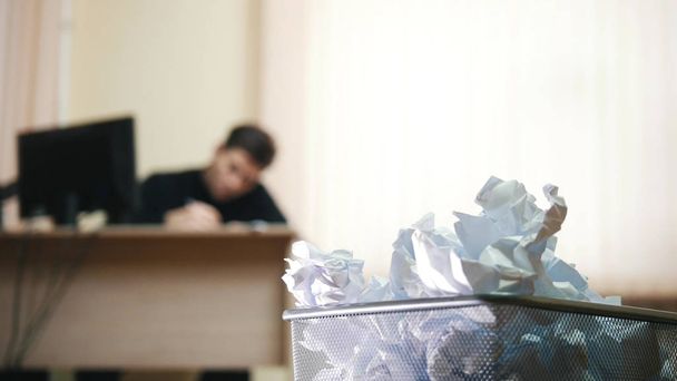 ein Mann im Büro schreibt etwas, konzentriert sich auf den Papierkorb. - Foto, Bild