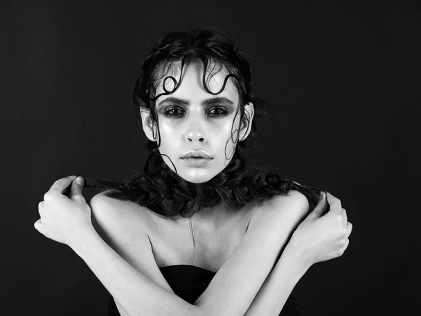 mulher com maquiagem brilhante segurando tranças com braços cruzados
 - Foto, Imagem