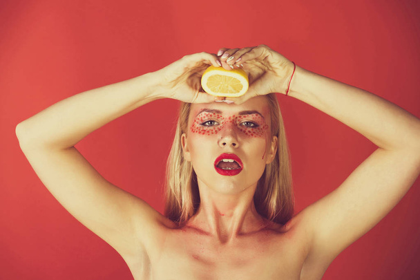 young girl squeeze yellow lemon on red background - 写真・画像