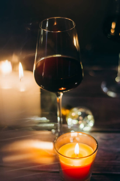Holidays composition made of glass of red wine, candles and garlands on a dark background - Foto, immagini