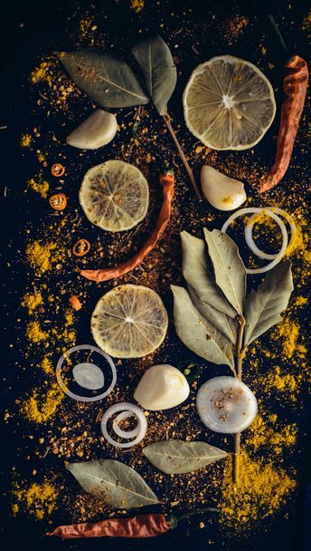 Set of spices: onion, lemon, garlic, red pepper, paprika, black pepper, caraway seeds, cumin, curry, laurel lea, turmeric, curcuma. Vitamin diet healthy spices food on dark background  - Photo, Image