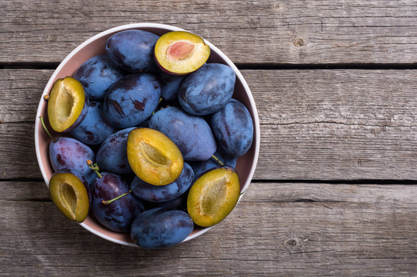 Fresh plums in bowl on wooden table . Fruit background - Foto, afbeelding