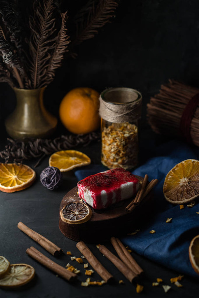 Christmas and New Year food concept. Cottage cheese pudding bake, curd pudding sweet dessert, cheesecake with black currant jam, strawberry jam, dried lemons, oranges, cinnamon on dark background. - Foto, Imagem