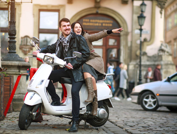 Happy young couple in love on a scooter in a tourist city - Fotoğraf, Görsel