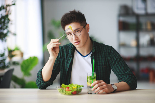 gezond eten. Gelukkig jonge man eten salade in de ochtend in garage - Foto, afbeelding