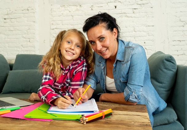 Beautiful mother helping her young blonde cute sweet girl to do homework at home in homework parenting and education concept. - Foto, Imagen