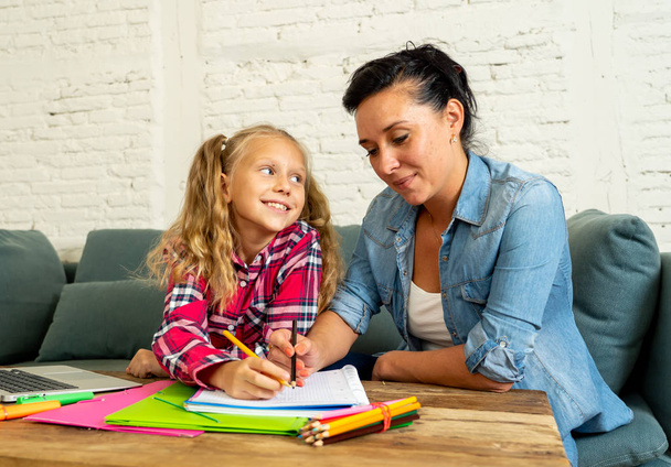 Beautiful mother helping her young blonde cute sweet girl to do homework at home in homework parenting and education concept. - Фото, зображення