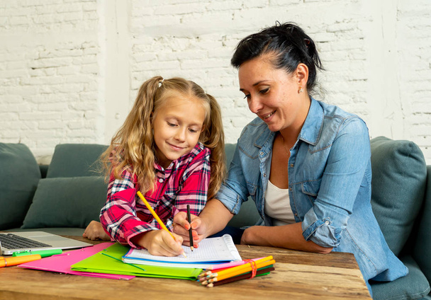 Belle mère aidant sa jeune fille douce et mignonne blonde à faire des devoirs à la maison dans le concept de parentalité et d'éducation aux devoirs
. - Photo, image