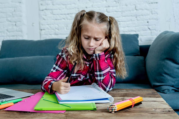 Cute elementary student feeling sad and confusing while doing difficult assignment with her laptop at home in primary school homework and children education concept. - Фото, зображення