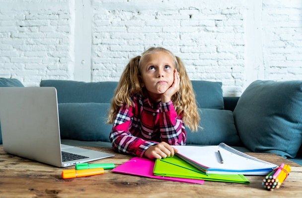 Cute elementary student feeling sad and confusing while doing difficult assignment with her laptop at home in primary school homework and children education concept. - Zdjęcie, obraz