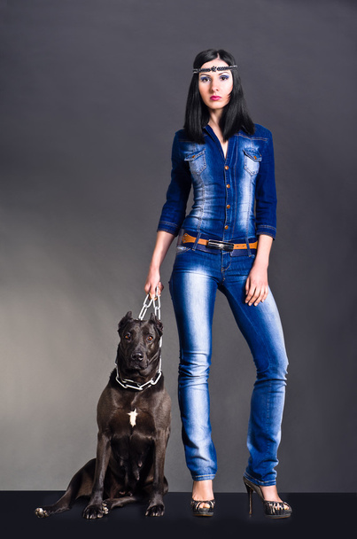 Beautiful young woman in jeans clothes standing next to a dog - Foto, afbeelding