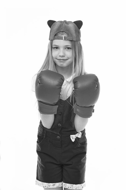 Lovely child wearing huge red boxing gloves. Girl in pink overalls isolated on white background. Kid wearing cute cap with animal ears backwards. Little fighter on training, self defence concept - Foto, immagini