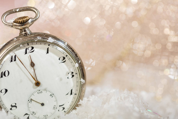New Years eve party celebration. Minutes to midnight on an old watch, bokeh snowy background, copy space - Photo, Image